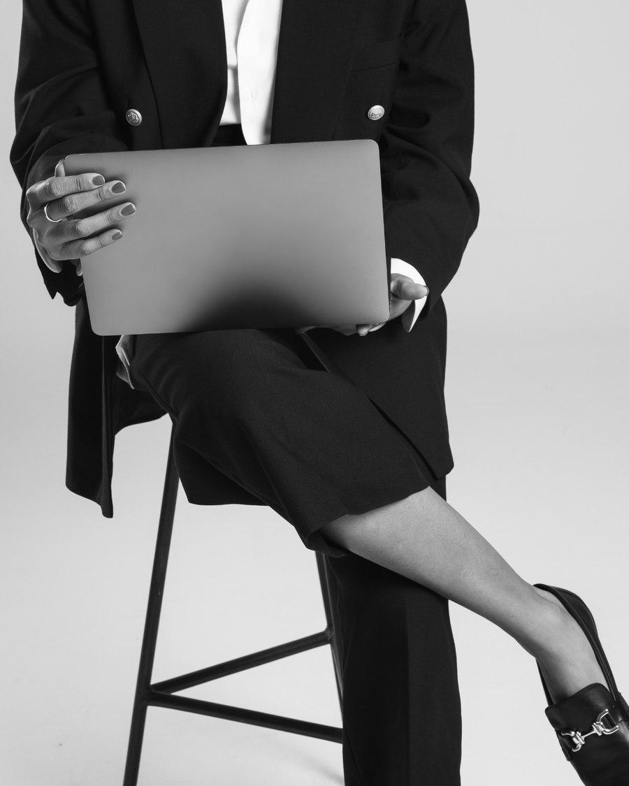 Woman in a black suit seated with a closed laptop